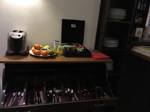 A kitchenette with a toaster, a fruit plate, a coffee maker, and a set of utensils. - Hotel Villa Stockum (Düsseldorf)
