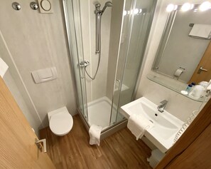 Ein modernes Badezimmer mit einer einbruchsicheren Duschkabine, einem weißen Waschbecken und einer Toilette.