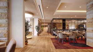 Un restaurant moderne avec un plancher en bois, une grande salle à manger avec des tables et des chaises, et un mur en briques sur l’un des côtés.