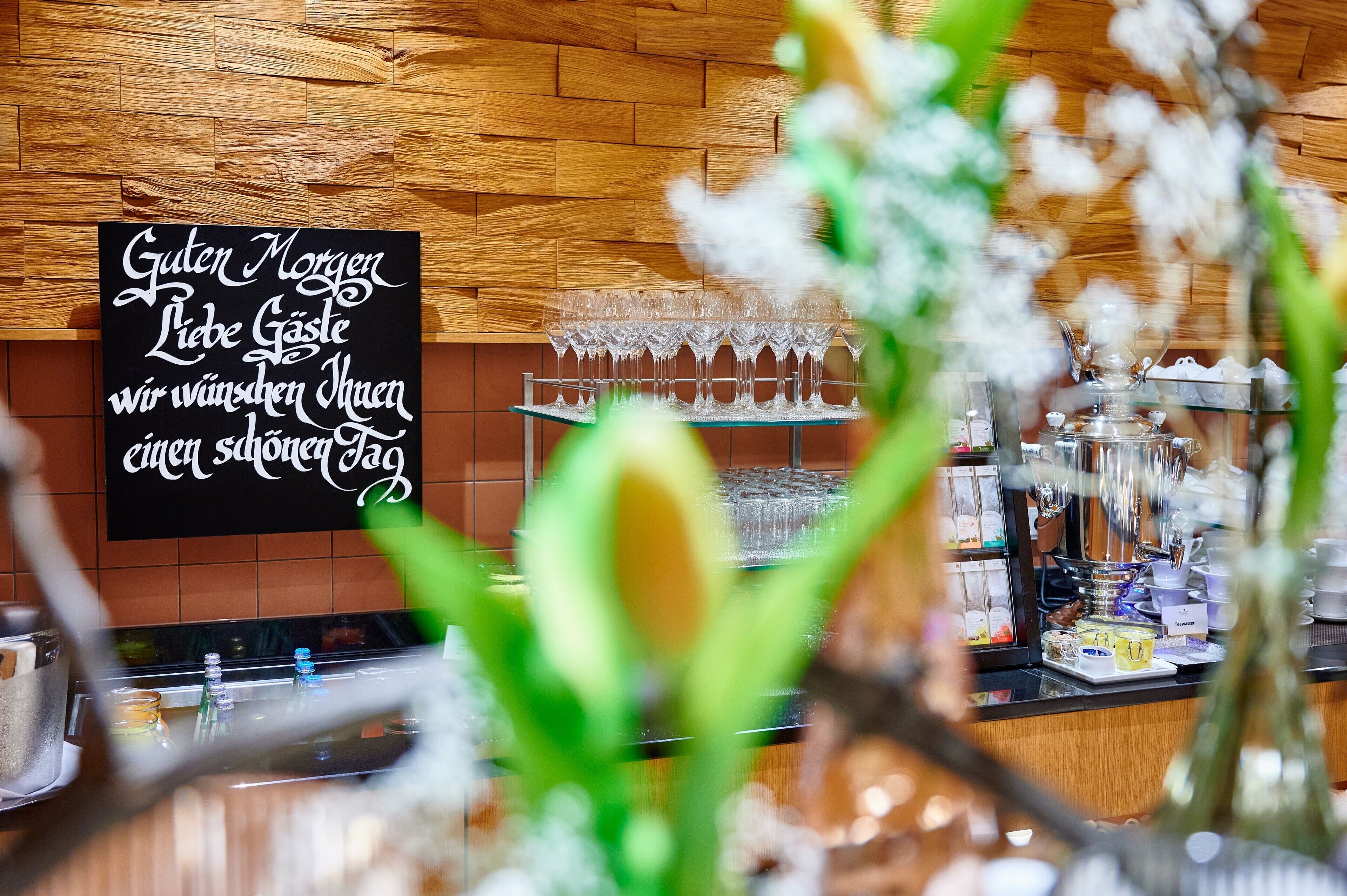 A restaurant interior with a wooden wall, a menu board, and a glass display case with various items.
