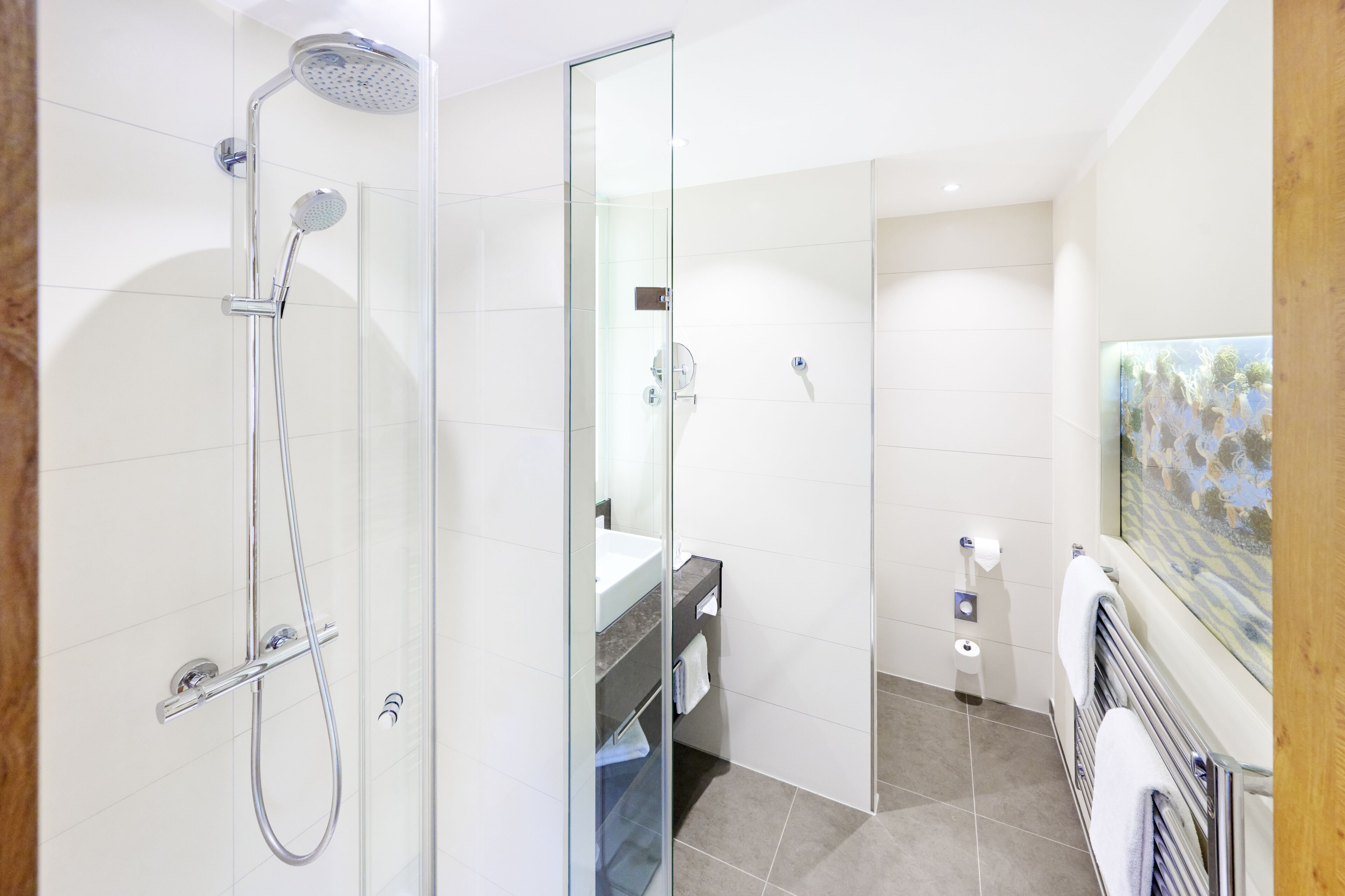 Un baño moderno con cabina de ducha de vidrio, tocador con lavabo y un perchero para toallas.