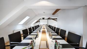 Ein Konferenzraum mit einem langen Tisch, schwarzen Stühlen und einem Holzbalken an der Decke.