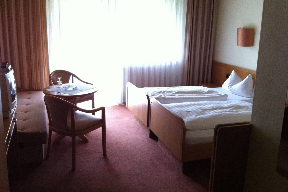 A hotel room with a bed, a small table with chairs, and a sofa.