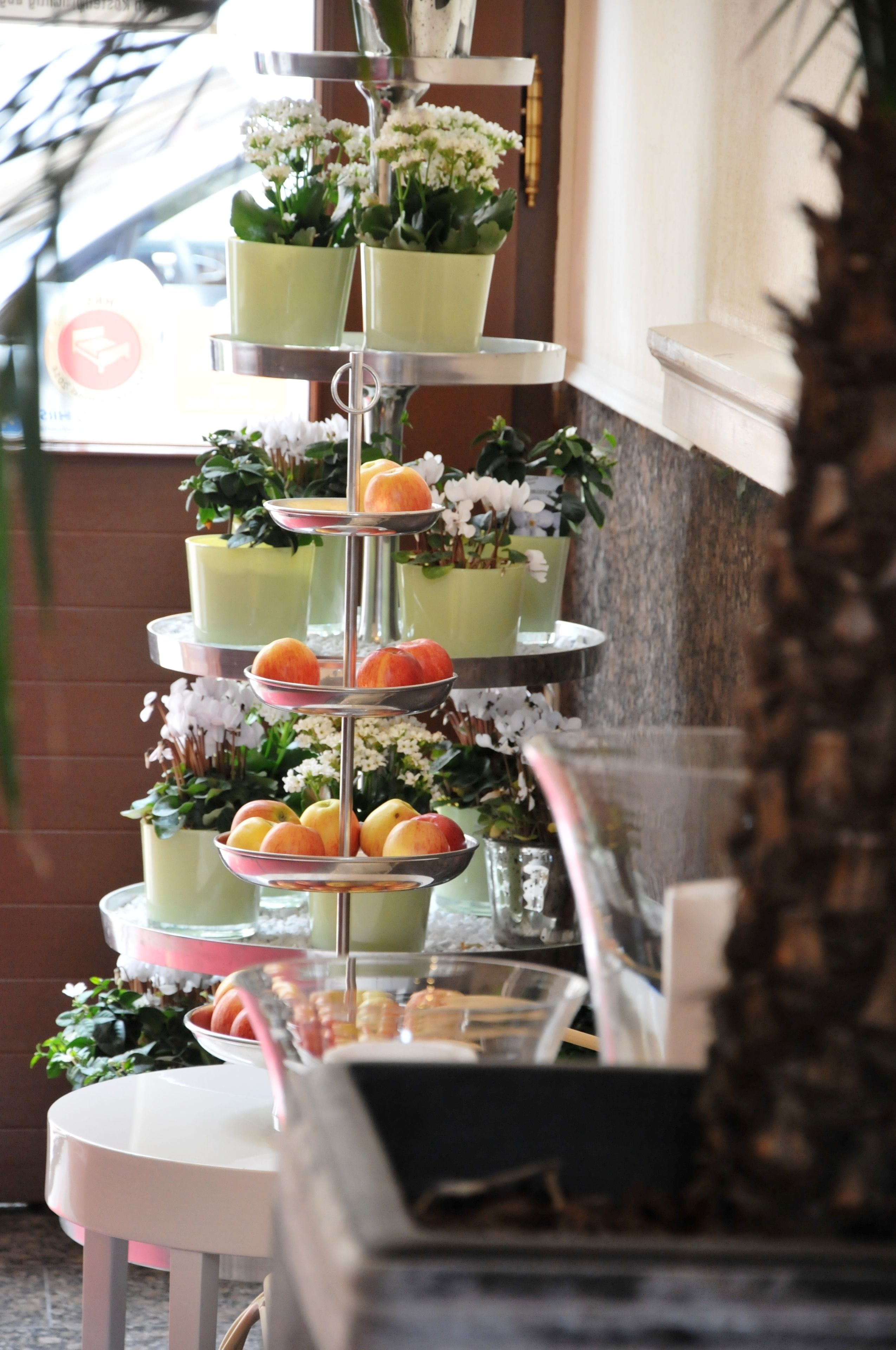 Un expositor escalonado con diversas frutas y flores.