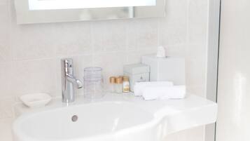 Un baño con lavamanos blanco, espejo y artículos de tocador.