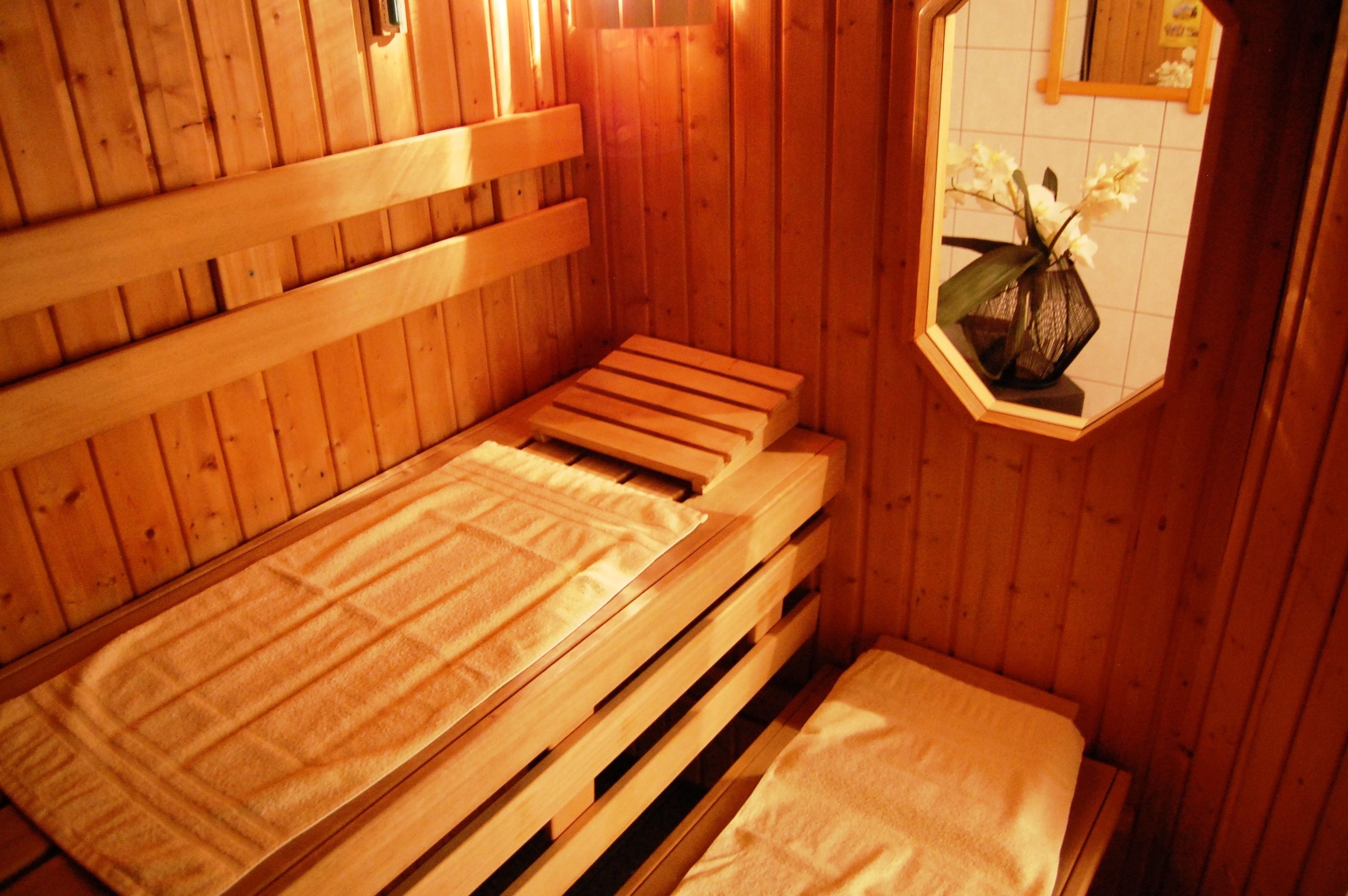 A wooden sauna with benches and a small window with a vase of flowers.