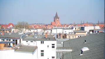 A cityscape with a prominent church with a tall spire, surrounded by residential buildings with red roofs.