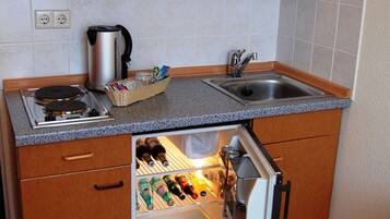 Una cocina compacta con estufa integrada, cafetera, lavaplatos y refrigerador con cajón para botellas de vino.