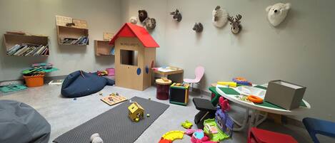 Un cuarto de juegos infantil con una casita, juguetes y material educativo.