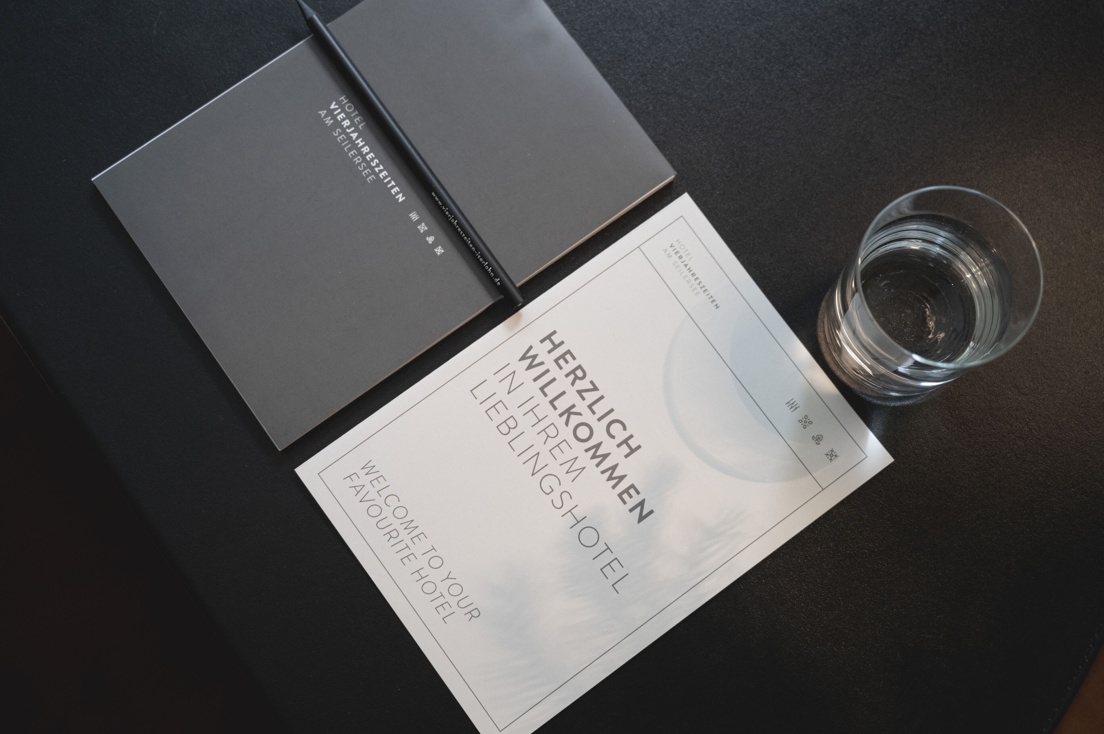 A hotel welcome card and a glass of water on a table.