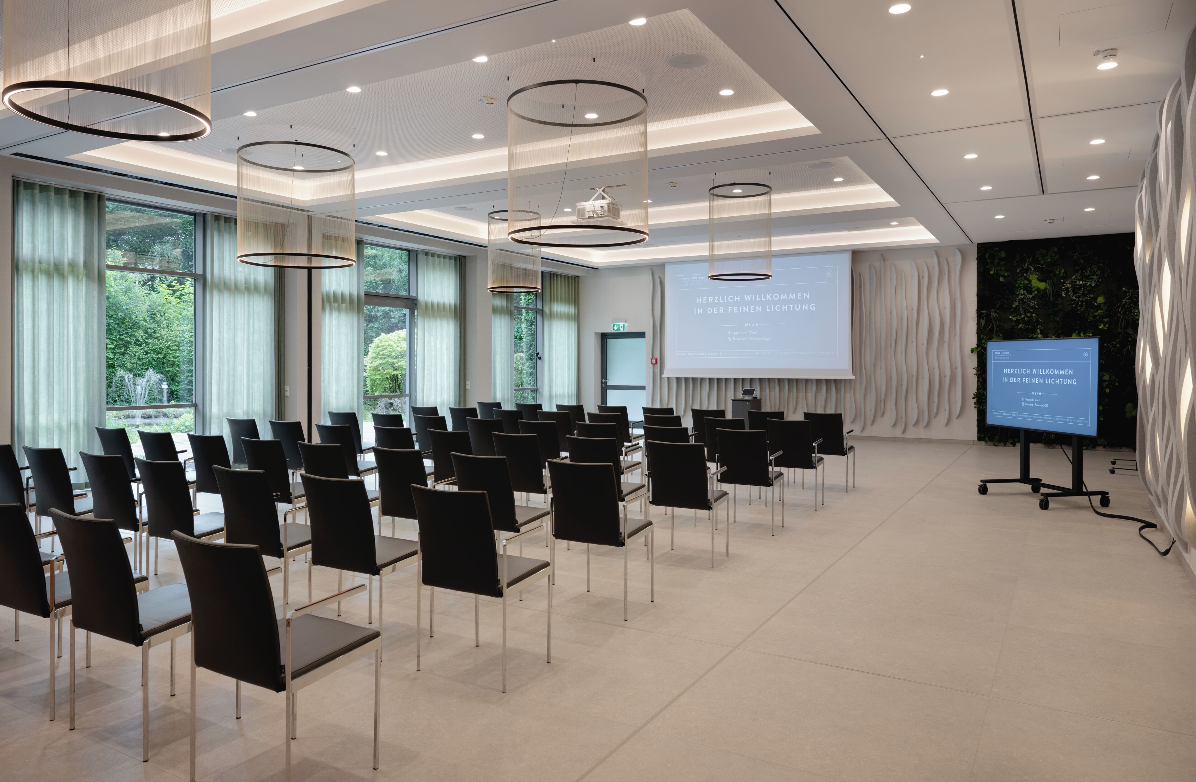 A conference room with rows of chairs, a projector screen, and a large window with curtains.