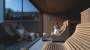 Un spa moderno con tumbonas de madera y un ventanal con vistas al exterior.