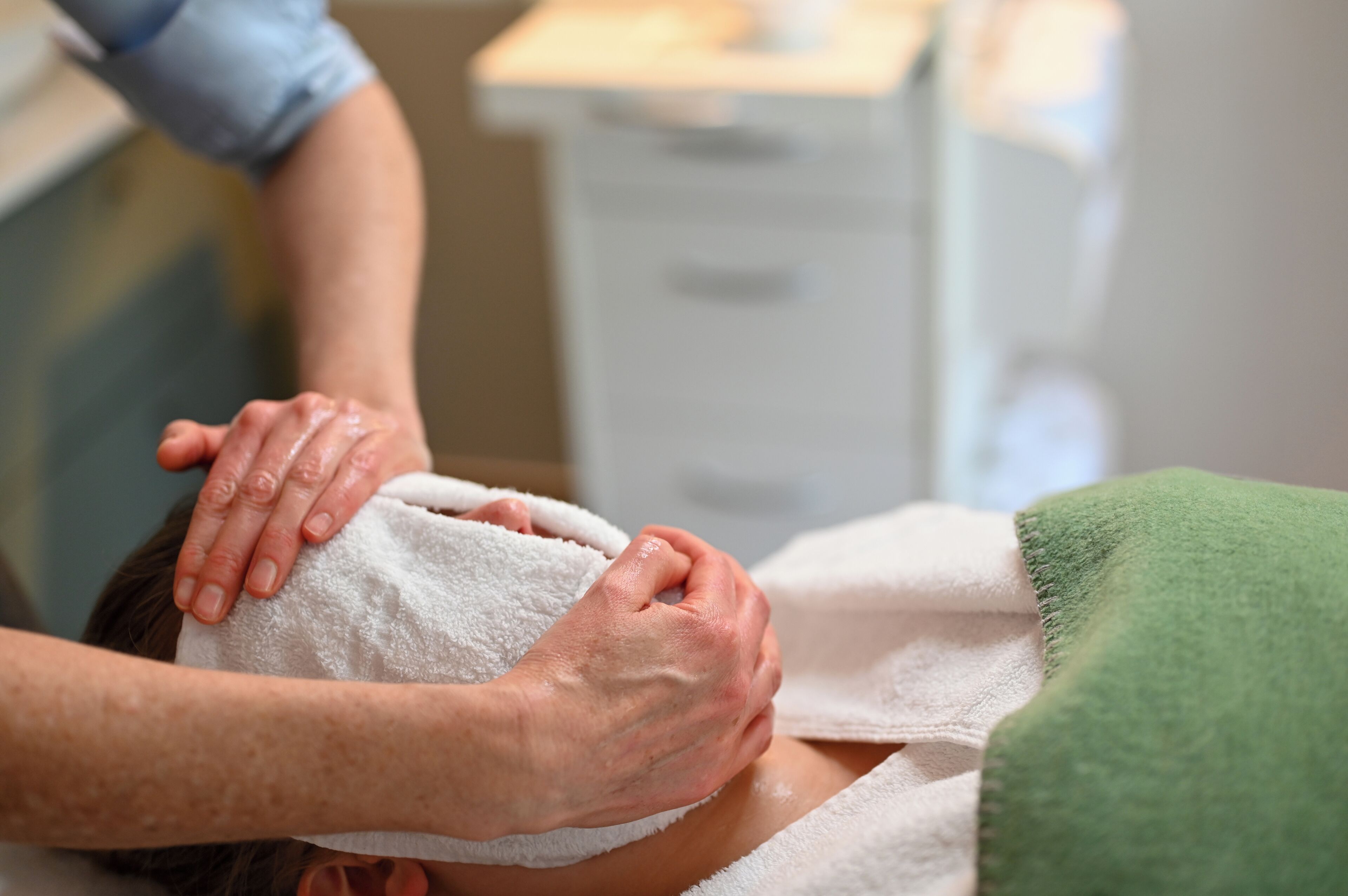 A person receiving a massage with a towel wrapped around their head.
