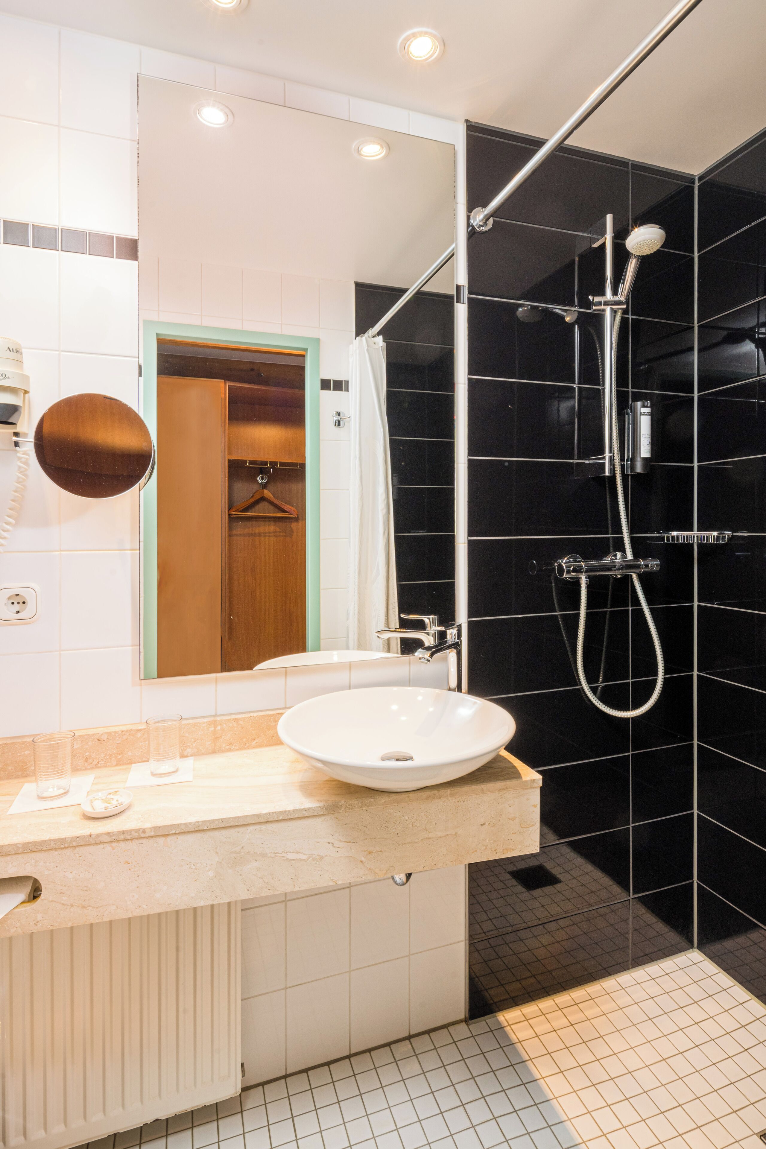 Ein modernes Badezimmer mit einem weißen Waschbecken, einem Spiegel und einer Dusche mit Duschbrause.