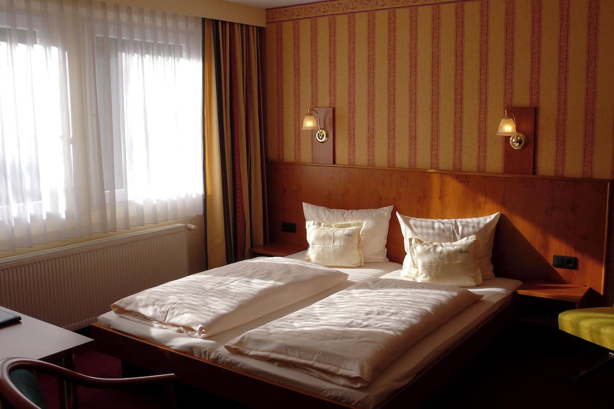 Une chambre d’hôtel avec un grand lit, deux tables de chevet, un bureau et une chaise.