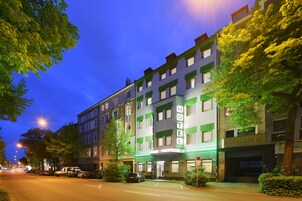 Un hotel con facciata verde e bianca, diversi piani e un ingresso ben visibile.