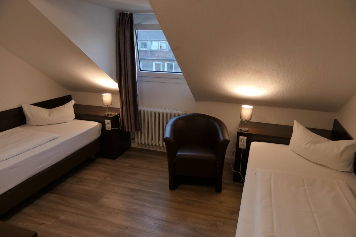 A room with two beds, a chair, and a window.