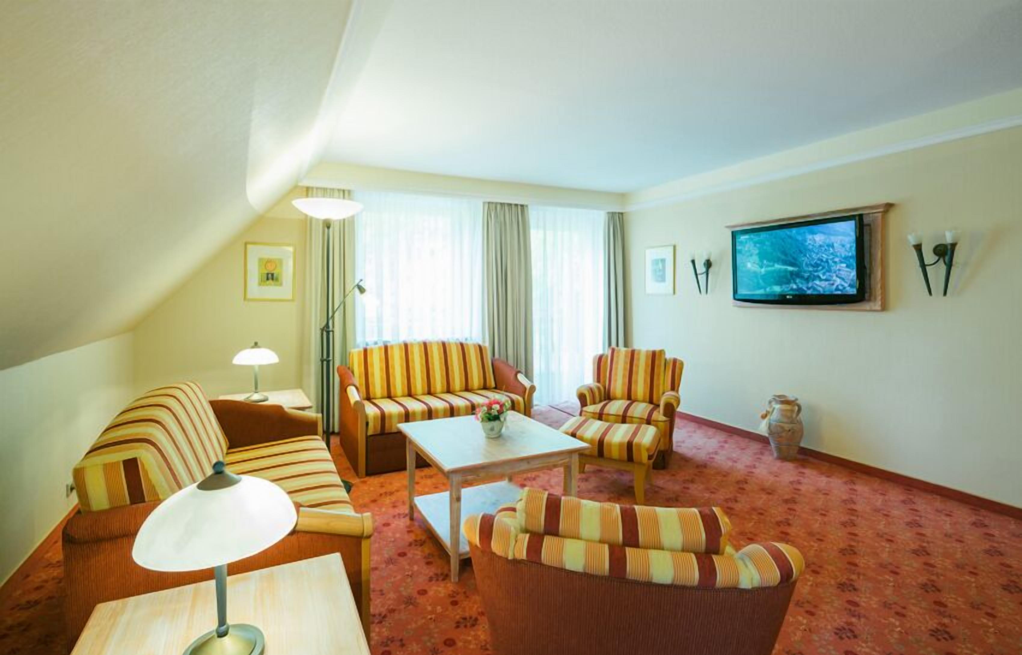 Ein gemütliches Wohnzimmer mit gestreiften Sofas, einem Couchtisch und einem an der Wand montierten Flachbildfernseher.