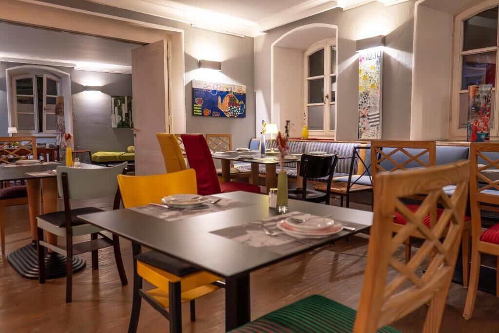 Un comedor con una mesa dispuesta para cuatro personas, rodeada de sillas con cojines.