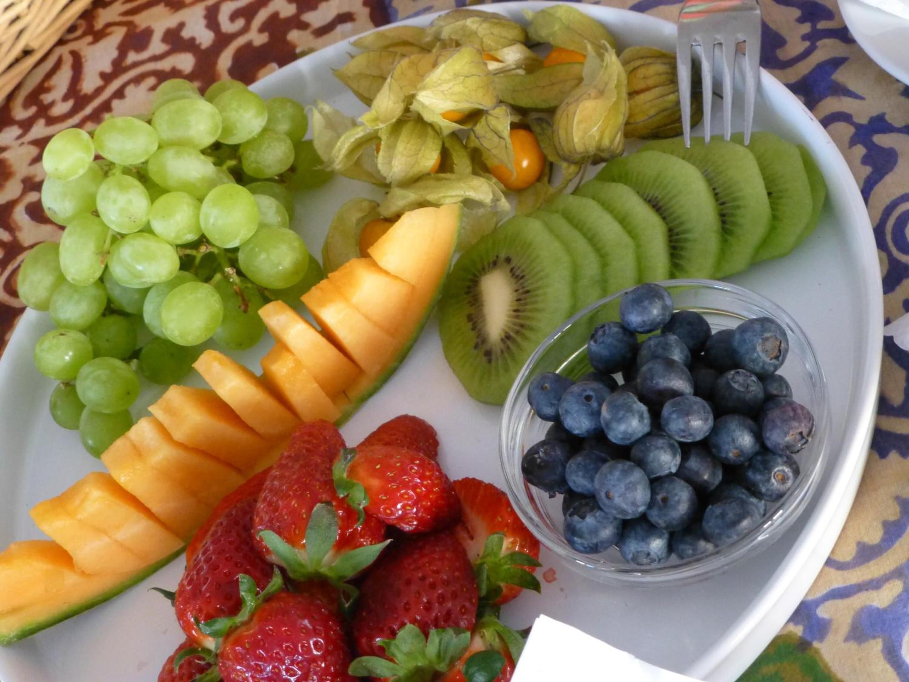 Un plato con frutas variadas, como uvas, kiwi, fresas, arándanos y melón en rodajas.