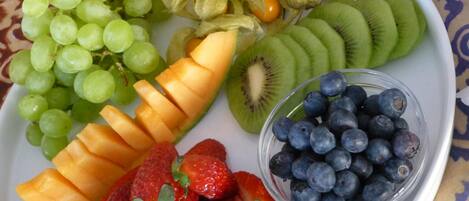 Un plato con frutas variadas, como uvas, kiwi, fresas, arándanos y melón en rodajas.