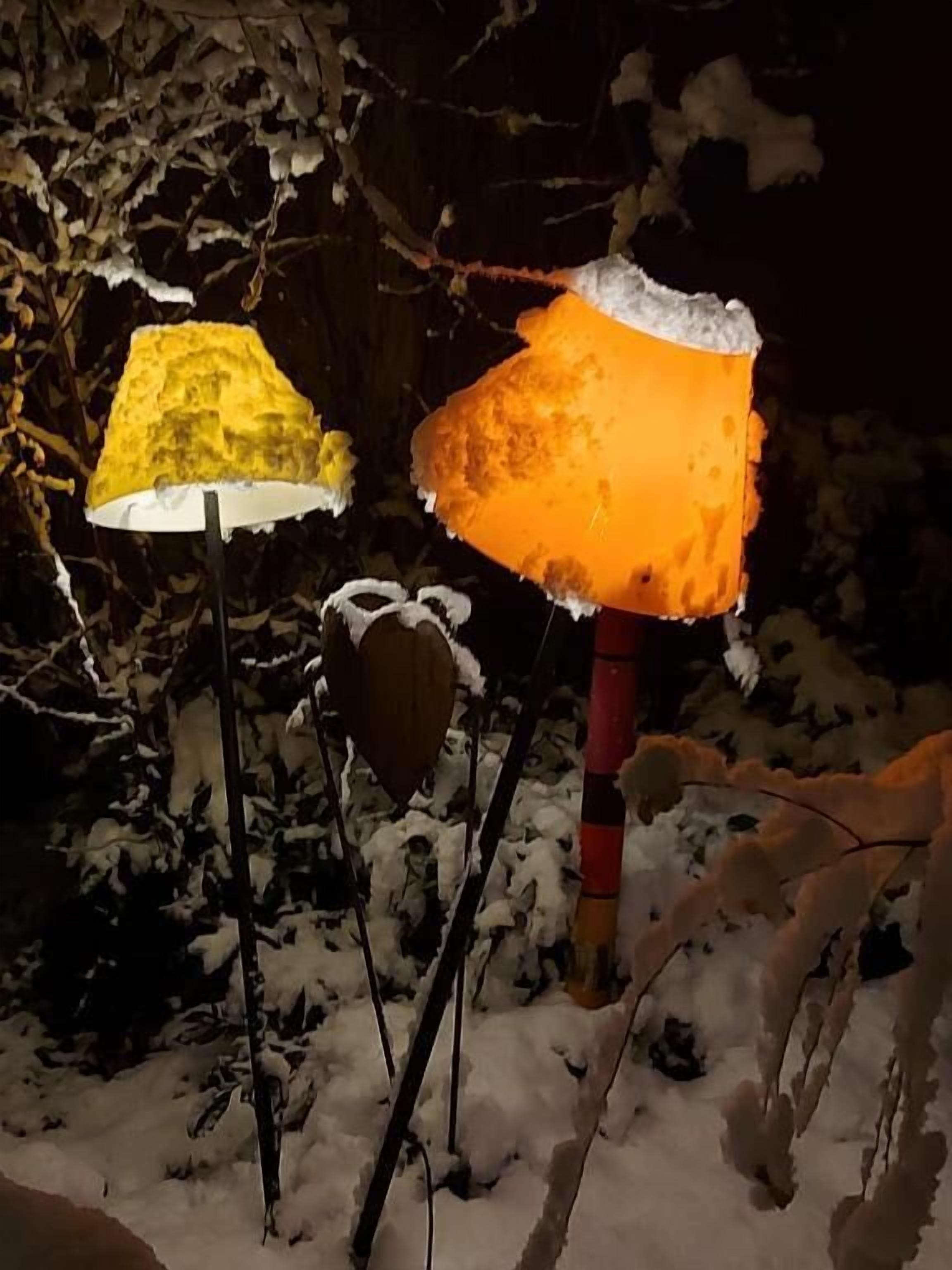 Two lamps with frosted covers, one yellow and one orange, set against a snowy background.