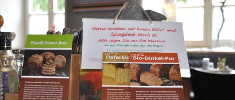 Exhibición de productos alimenticios con descripciones en alemán, incluyendo 'Eiweiß-Power-Brot' y 'Haferkörle Bio-Dinkel-Pur'.