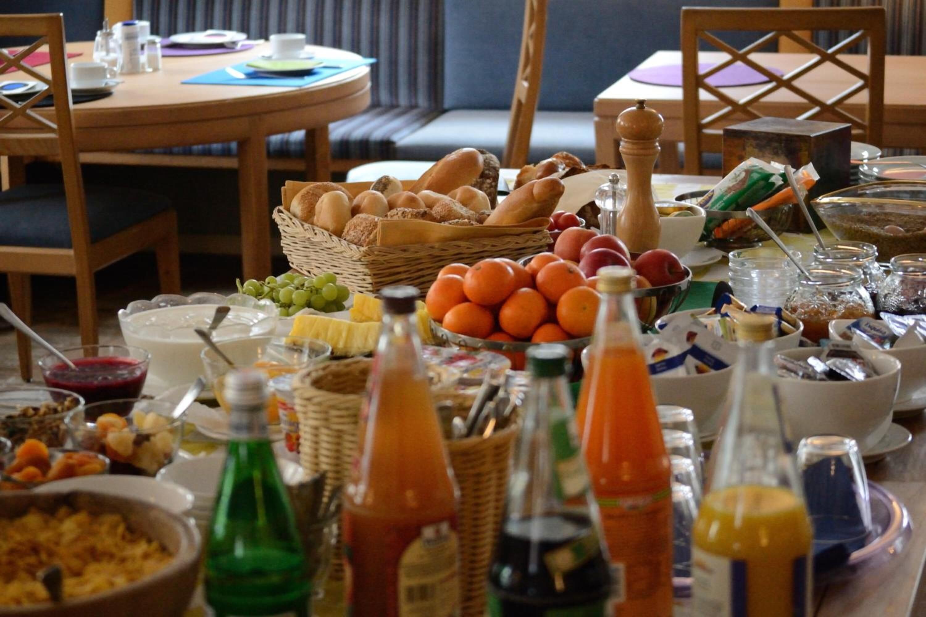 A breakfast buffet with various breads, fruits, and beverages.