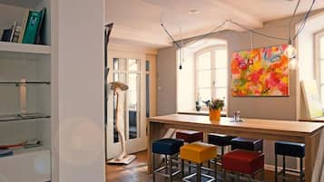 Una cucina moderna con angolo bar, sgabelli di legno e un quadro astratto dai colori vivaci.