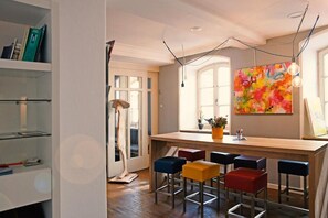 Una cocina moderna con barra, taburetes de madera y un cuadro abstracto de colores.