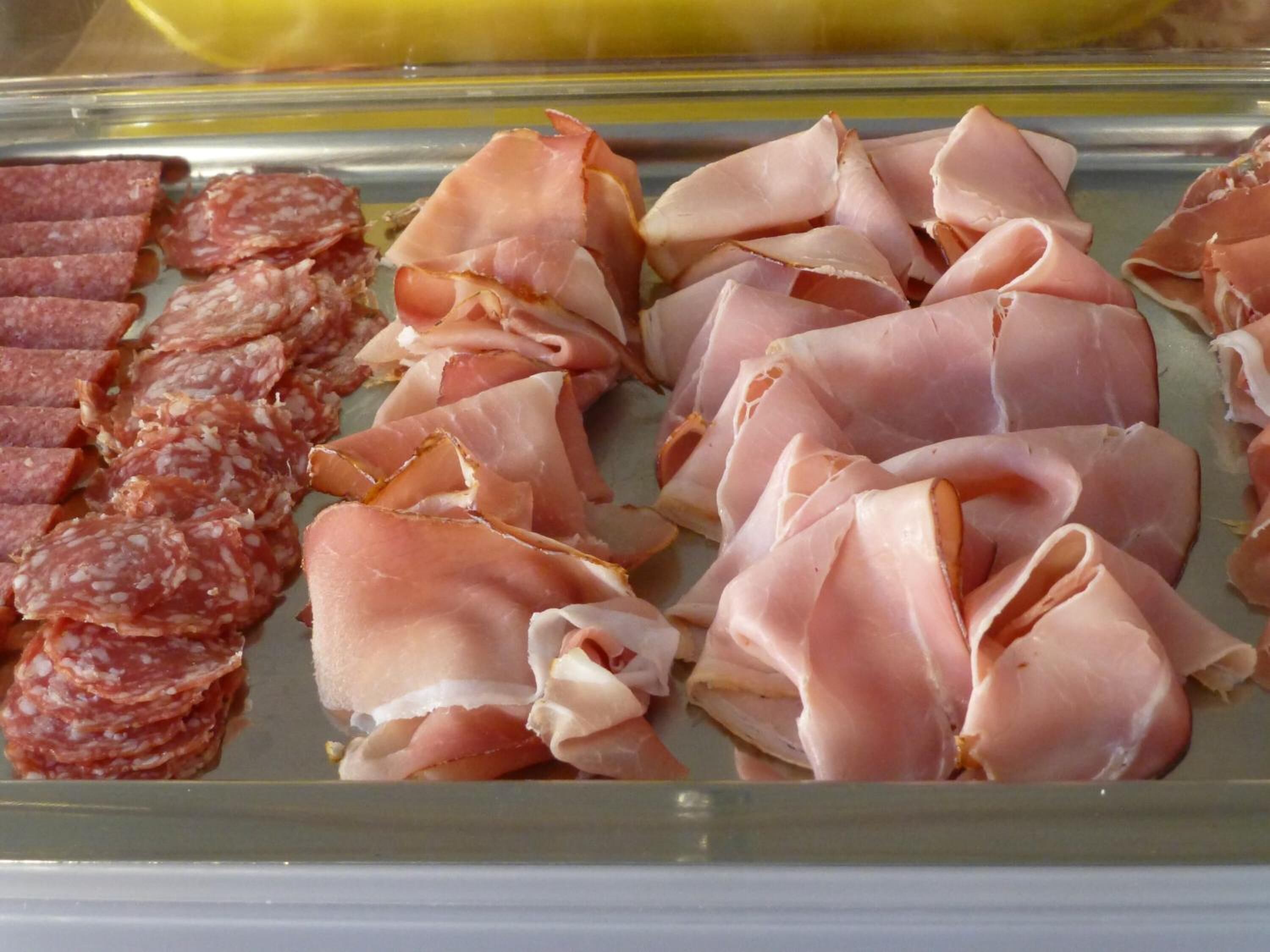 Una bandeja con exhibición de embutidos en rodajas, incluyendo salchichón y jamón serrano.