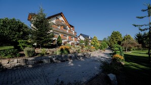 A multi-story hotel with a stone pathway leading to the entrance, surrounded by well-maintained gardens and trees. - Hotel-Gasthof Rose (Oberkirch)