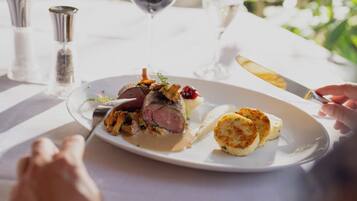 A plate of food with a steak, vegetables, and a side dish, set on a table with salt and pepper shakers.