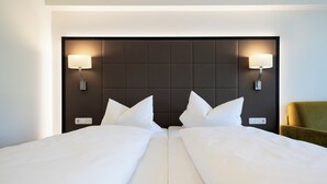 A hotel room with a large bed, two bedside lamps, and a green armchair. - Hotel-Gasthof Rose (Oberkirch)