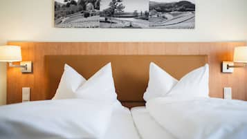 A hotel room with a wooden headboard, white bedding, and two wall-mounted lamps.
