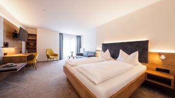 Una habitación de hotel moderna con una cama grande, un escritorio, una silla, un televisor y una estantería.