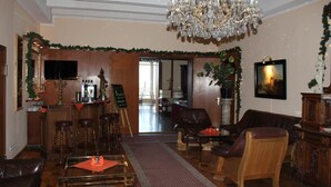 A spacious living room with a chandelier, leather furniture, and a bar area. - Hotel Stolteraa (Rostock)