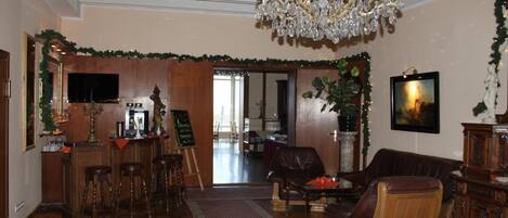 A spacious living room with a chandelier, leather furniture, and a bar area.