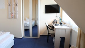 A hotel room with a bed, a desk with a chair, a television, and a closet with a mirror. - Hotel Stolteraa (Rostock)