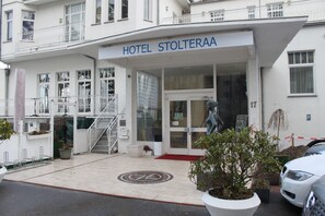 Een hotelentree met een bord waarop 'HOTEL STOLTERAA' staat.