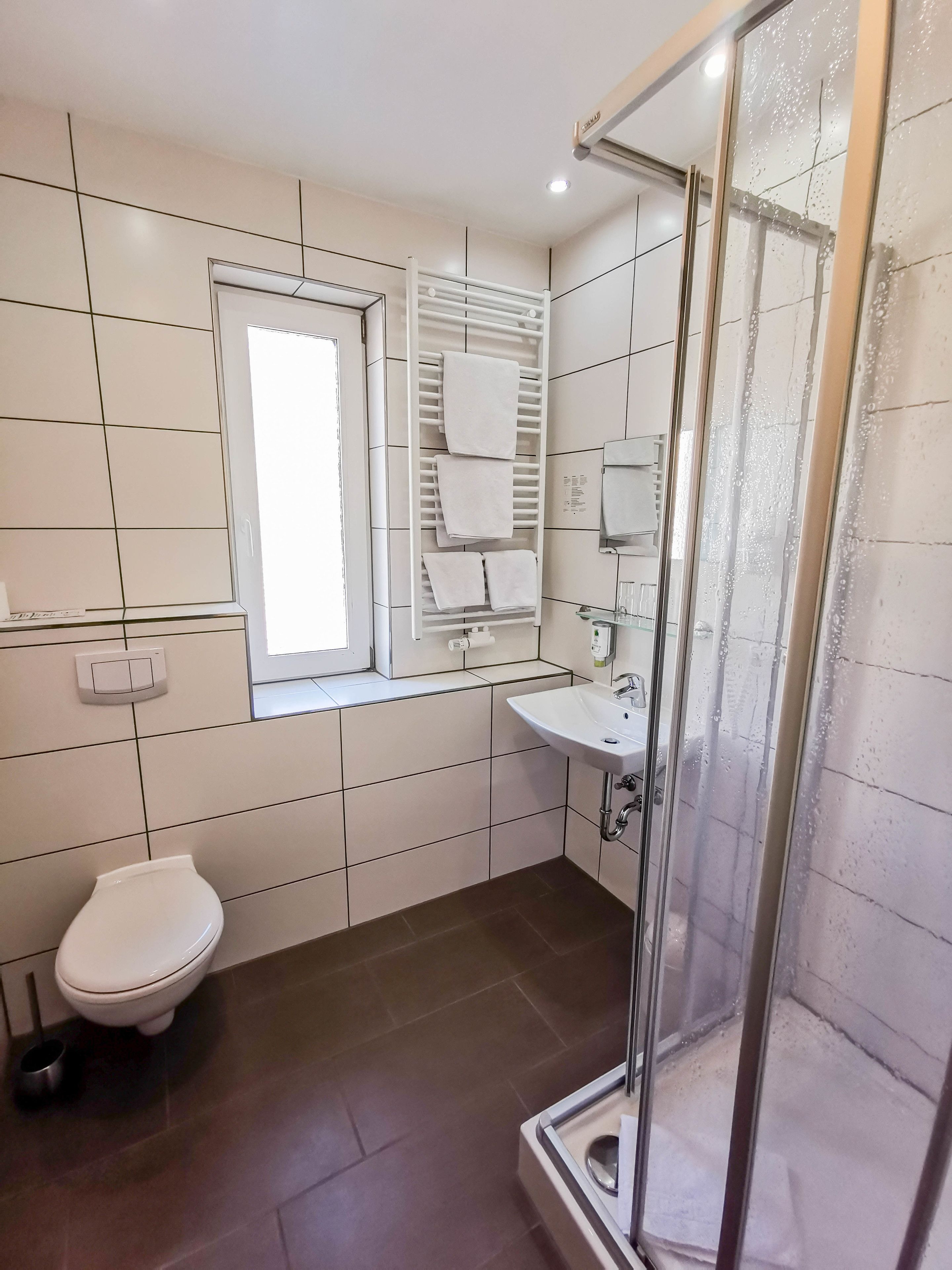 Een moderne badkamer met toilet, wastafel en douche.