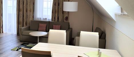 Un salon moderne comprenant un canapé, des fauteuils, une table à manger et une lampe.