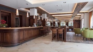 A spacious lobby with a wooden reception desk, multiple seating areas, and large windows providing natural light. - Hotel Strasshof (Pfaffenhofen an der Ilm)