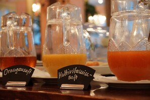 Una barra de buffet con dispensadores de zumo etiquetados para zumo de naranja y bebidas multivitamínicas.
