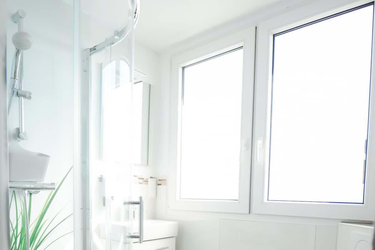 A modern bathroom with a glass-enclosed shower, a white sink, and a toilet.