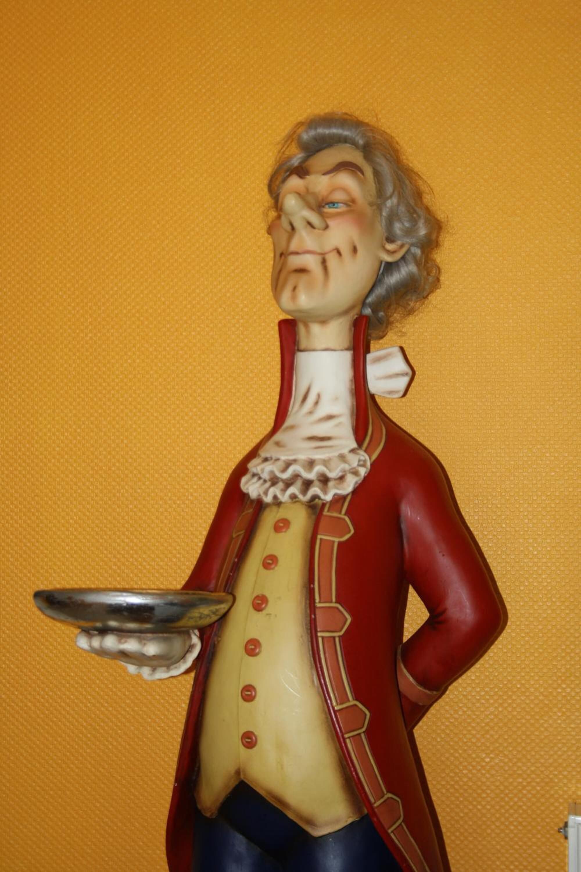 A statue of a man in historical attire holding a plate.