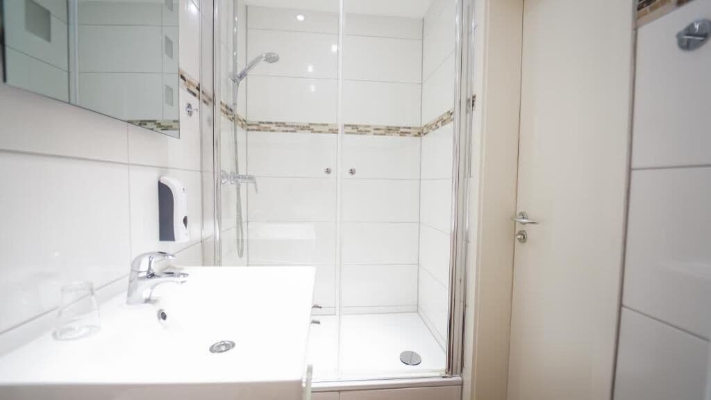 Een badkamer met een douchecabine, een wastafel met spiegel en een toilet.