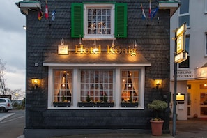 A building with a sign reading "Hotel König" and a restaurant sign next to it.