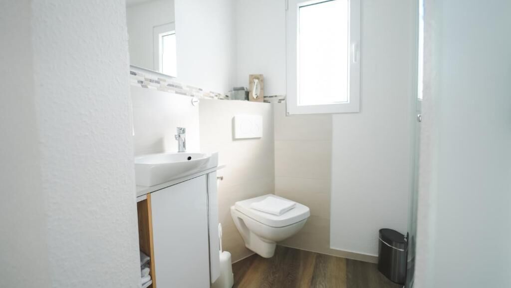 A small, white bathroom with a toilet, sink, and a mirror above the sink.