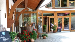 A building entrance with a wooden facade, large windows, and potted plants. - Hotel Weinklause (Oberstdorf)
